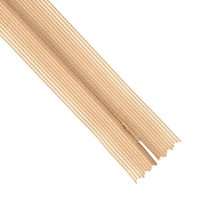 End part of a beige invisible zipper on a white background.