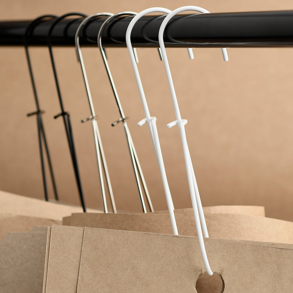 White pattern hooks on a black rod against a beige background