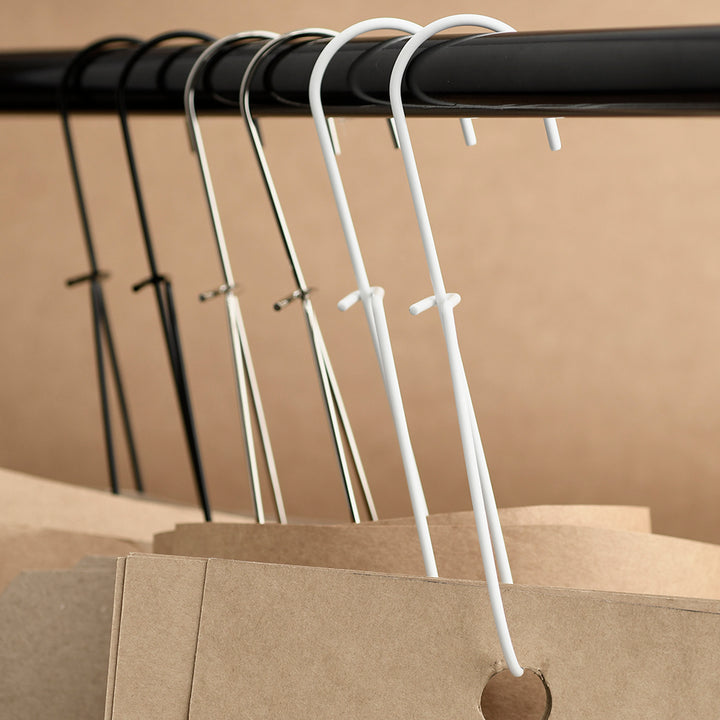 White pattern hooks on a black rod against a beige background