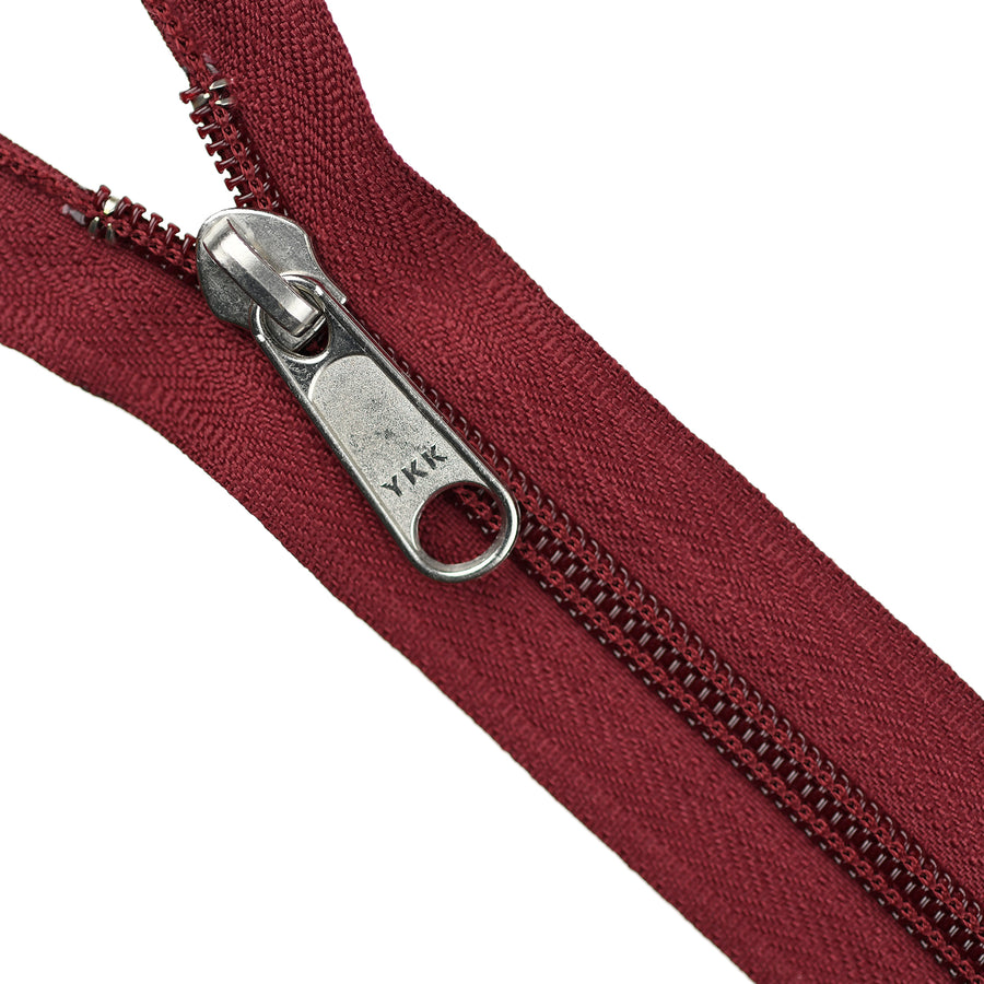 Maroon zipper with silver YKK pull on a white background